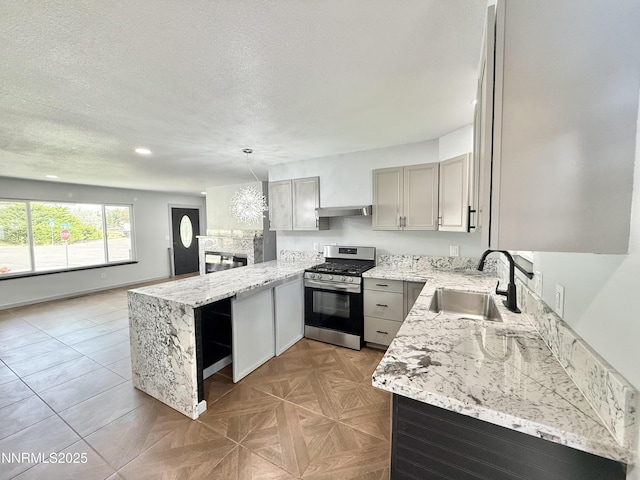 603 Camelot Way, Winnemucca, NV 89445 - kitchen with gas range, a sink, a peninsula, under cabinet range hood, and light stone countertops