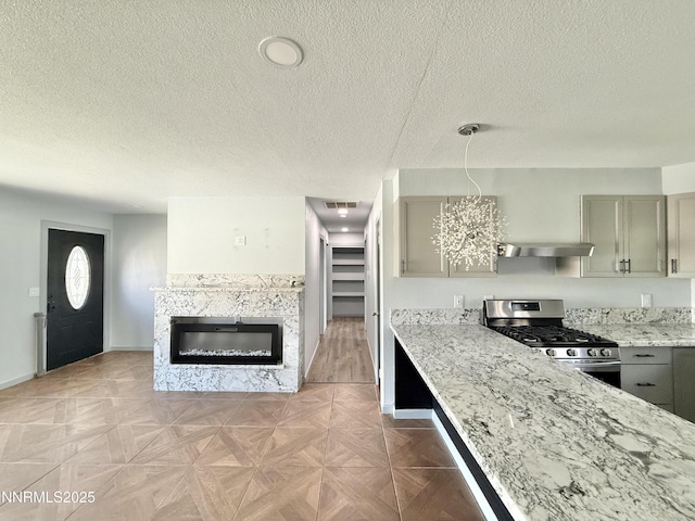 603 Camelot Way, Winnemucca, NV 89445 - kitchen featuring stainless steel gas range, ventilation hood, a textured ceiling, gray cabinets, and baseboards