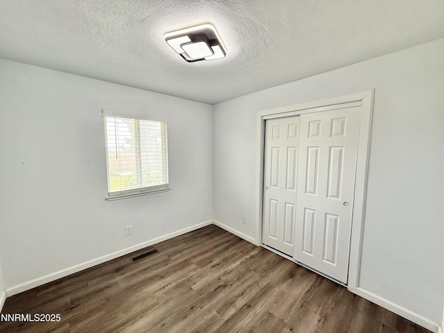 603 Camelot Way, Winnemucca, NV 89445 - unfurnished bedroom with dark wood-type flooring, a closet, baseboards, and a textured ceiling