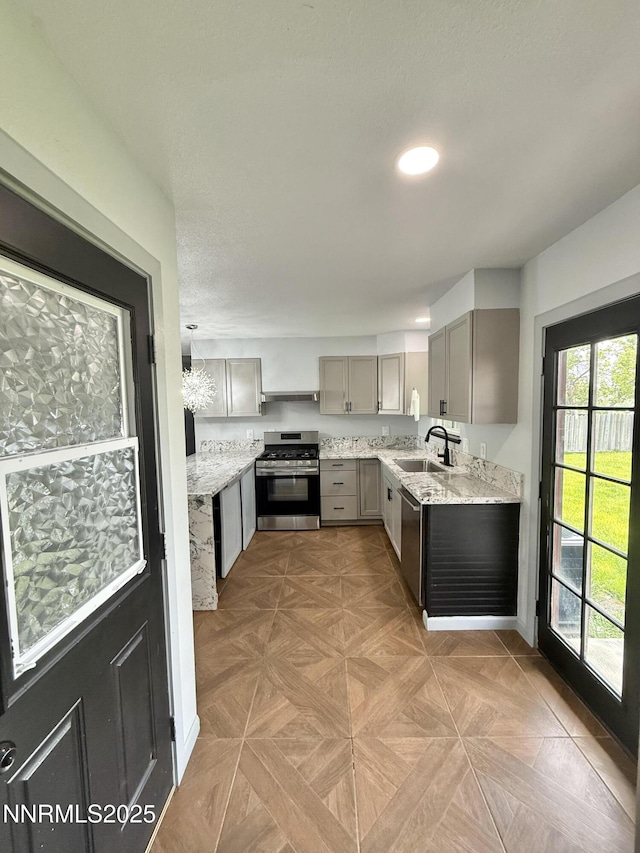 603 Camelot Way, Winnemucca, NV 89445 - kitchen featuring appliances with stainless steel finishes, gray cabinets, a sink, light stone countertops, and exhaust hood
