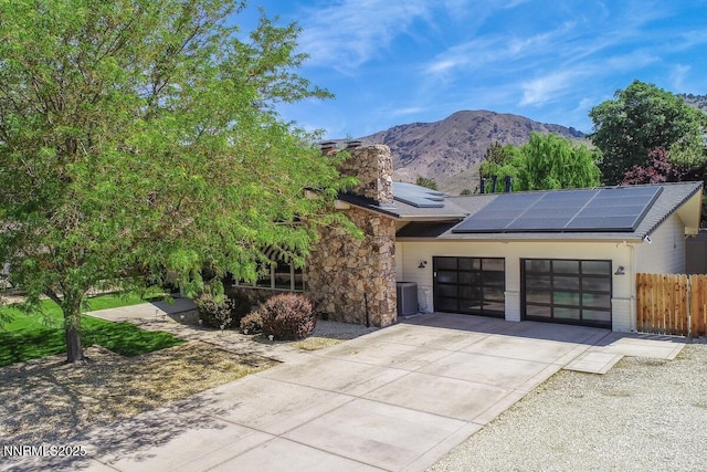 5000 Saint Andrews Dr, Reno, NV 89502 - view of front of house featuring an attached garage, roof mounted solar panels, concrete driveway, a mountain view, and stone siding
