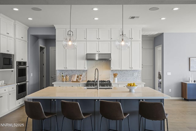 9192 Graycliff Ln, Reno, NV 89523 - kitchen featuring stainless steel appliances, under cabinet range hood, backsplash, light wood finished floors, and recessed lighting