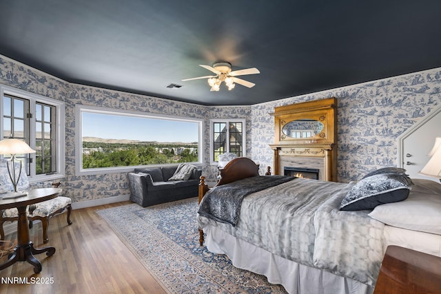 745 California Ave, Reno, NV 89509 - bedroom with wallpapered walls, baseboards, wood finished floors, a lit fireplace, and a ceiling fan