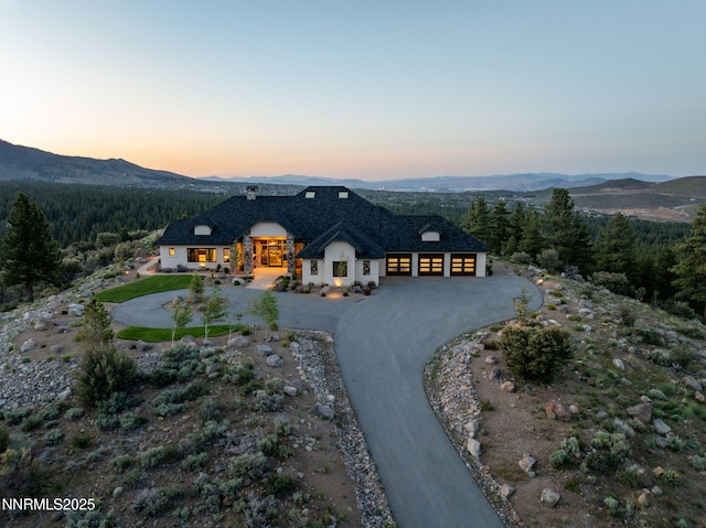 29 Bennington Ct, Reno, NV 89511 - french country style house featuring a garage, a mountain view, curved driveway, and a wooded view