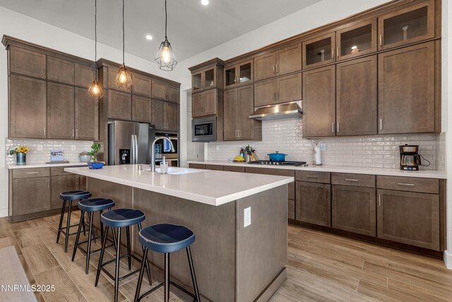 611 Camargue Trl, Reno, NV 89511 - kitchen featuring stainless steel appliances, a sink, under cabinet range hood, tasteful backsplash, and a kitchen breakfast bar