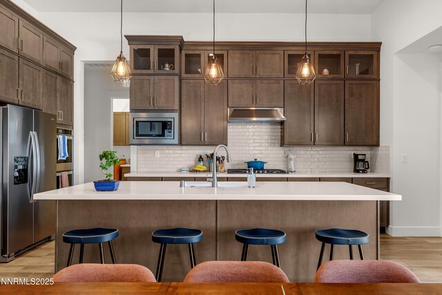611 Camargue Trl, Reno, NV 89511 - kitchen with appliances with stainless steel finishes, light wood-style flooring, under cabinet range hood, a breakfast bar, and light countertops