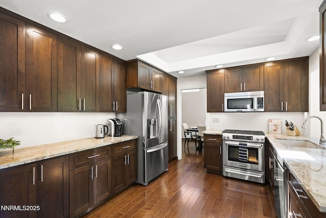 6055 Stonecreek Dr, Reno, NV 89511 - kitchen with appliances with stainless steel finishes, a raised ceiling, dark wood finished floors, light stone counters, and recessed lighting