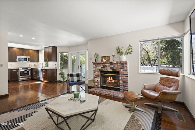 6055 Stonecreek Dr, Reno, NV 89511 - living area featuring dark wood-style floors, a brick fireplace, recessed lighting, bar, and french doors