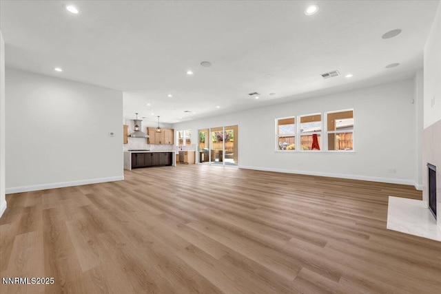 9740 Cardigan Bay Ln, Reno, NV 89521 - unfurnished living room with recessed lighting, light wood-type flooring, and a fireplace with flush hearth