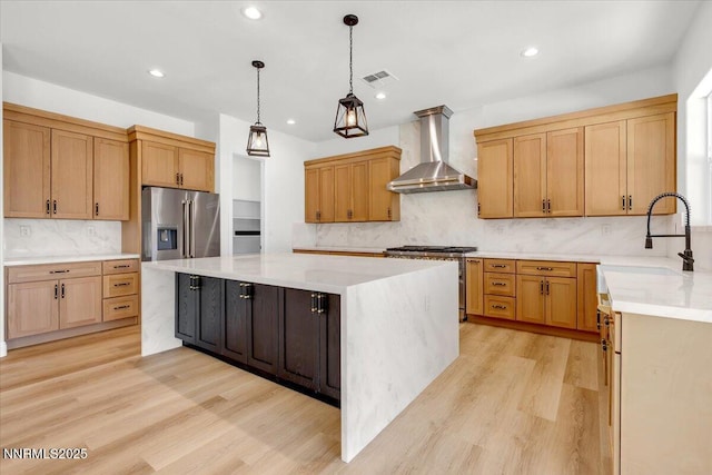 9740 Cardigan Bay Ln, Reno, NV 89521 - kitchen featuring appliances with stainless steel finishes, wall chimney range hood, tasteful backsplash, a kitchen island, and light wood-style flooring