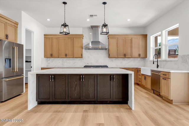 9740 Cardigan Bay Ln, Reno, NV 89521 - kitchen with stainless steel appliances, wall chimney exhaust hood, light wood-type flooring, light countertops, and a center island