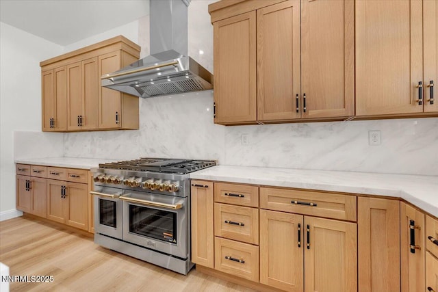 9740 Cardigan Bay Ln, Reno, NV 89521 - kitchen with wall chimney exhaust hood, range with two ovens, tasteful backsplash, light wood-style floors, and light brown cabinetry