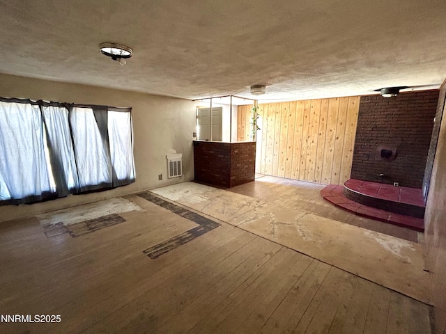 4082 Grass Valley Rd, Winnemucca, NV 89445 - unfurnished living room with hardwood / wood-style floors, a textured ceiling, and wood walls