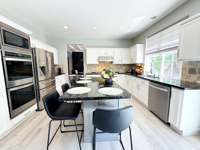 6726 Runnymede Dr, Sparks, NV 89436 - kitchen with appliances with stainless steel finishes, a sink, under cabinet range hood, a kitchen breakfast bar, and tasteful backsplash