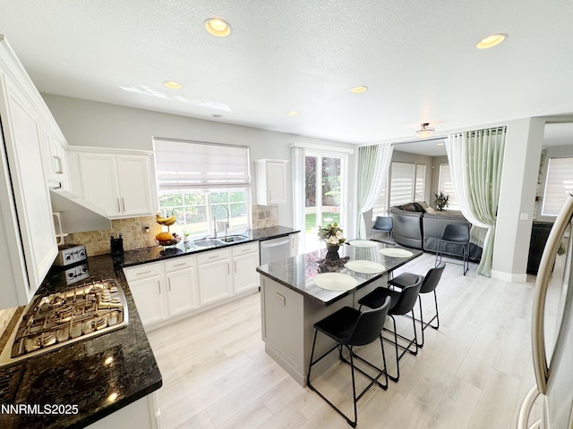 6726 Runnymede Dr, Sparks, NV 89436 - kitchen with appliances with stainless steel finishes, tasteful backsplash, a kitchen breakfast bar, white cabinetry, and recessed lighting