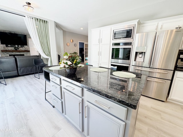 6726 Runnymede Dr, Sparks, NV 89436 - kitchen with stainless steel appliances, light wood-style flooring, white cabinets, dark stone countertops, and open floor plan