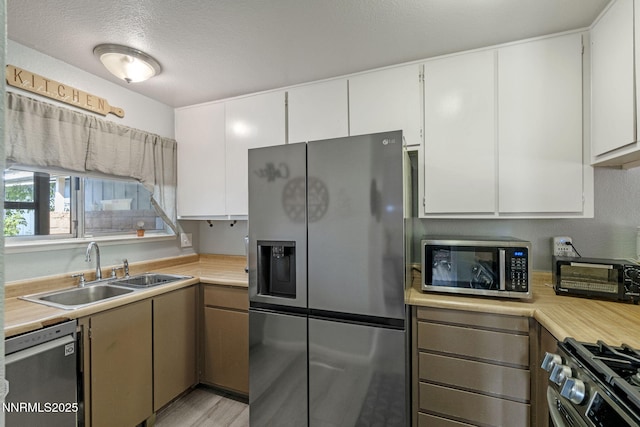 11050 Zeolite Dr, Reno, NV 89506 - kitchen featuring stainless steel appliances, a sink, light countertops, white cabinets, and a textured ceiling