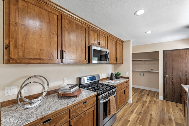 295 Sandia Dr, Fernley, NV 89408 - kitchen with appliances with stainless steel finishes, brown cabinets, light wood-style flooring, a textured ceiling, and baseboards