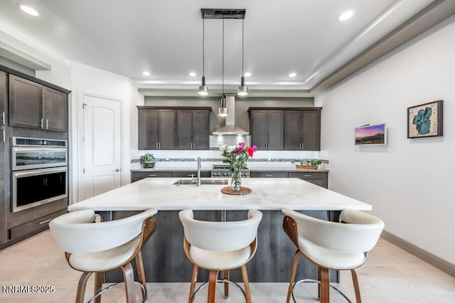 1536 Elk Run Trl, Reno, NV 89523 - kitchen with wall chimney range hood, a sink, a breakfast bar, dark brown cabinetry, and recessed lighting
