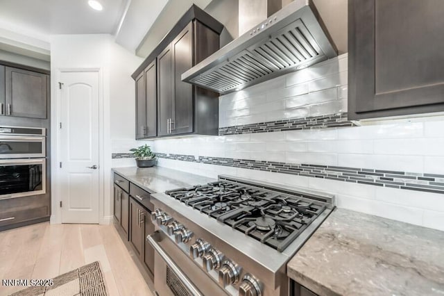 1536 Elk Run Trl, Reno, NV 89523 - kitchen featuring stainless steel appliances, wall chimney range hood, light stone countertops, light wood-style flooring, and recessed lighting