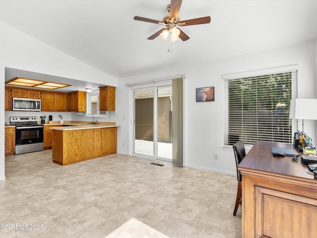 1772 Shamrock Cir, Minden, NV 89423 - kitchen featuring stainless steel appliances, lofted ceiling, brown cabinetry, a peninsula, and a ceiling fan