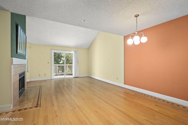2875 Idlewild Dr Unit 106, Reno, NV 89509 - unfurnished living room with a textured ceiling, light wood-style flooring, a tile fireplace, baseboards, and a chandelier