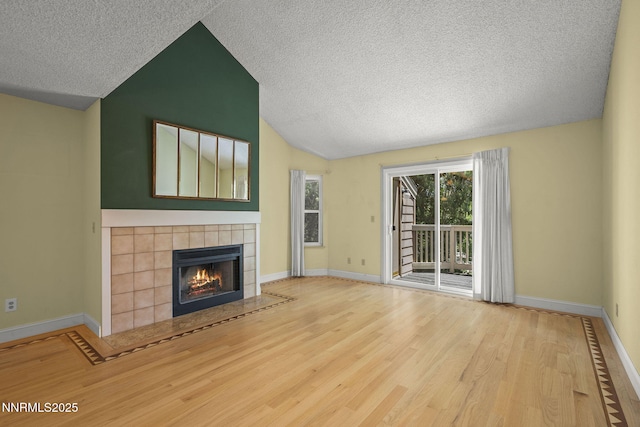 2875 Idlewild Dr Unit 106, Reno, NV 89509 - unfurnished living room featuring vaulted ceiling, wood finished floors, a textured ceiling, baseboards, and a tile fireplace