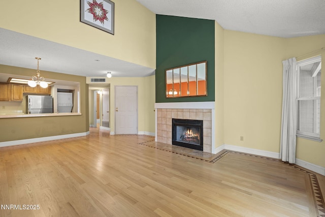 2875 Idlewild Dr Unit 106, Reno, NV 89509 - unfurnished living room with light wood-style floors, a tile fireplace, high vaulted ceiling, and baseboards