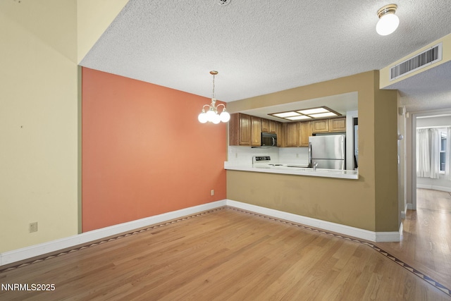 2875 Idlewild Dr Unit 106, Reno, NV 89509 - kitchen featuring black microwave, freestanding refrigerator, stove, brown cabinetry, and light wood-style flooring