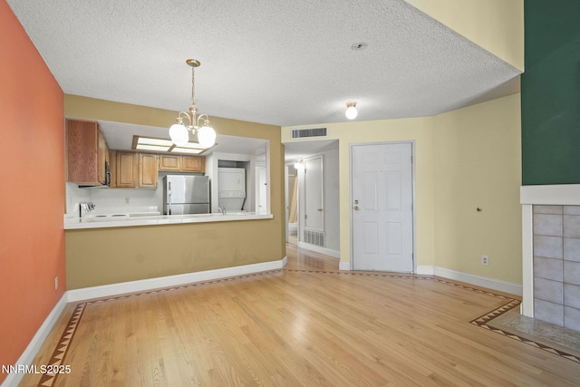 2875 Idlewild Dr Unit 106, Reno, NV 89509 - kitchen featuring freestanding refrigerator, light wood-style flooring, a textured ceiling, brown cabinetry, and baseboards