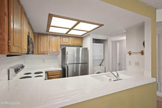 2875 Idlewild Dr Unit 106, Reno, NV 89509 - kitchen featuring freestanding refrigerator, range with electric cooktop, stacked washer / dryer, a sink, and a peninsula