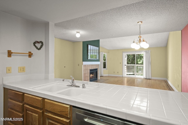 2875 Idlewild Dr Unit 106, Reno, NV 89509 - kitchen with a sink, open floor plan, a tile fireplace, a chandelier, and a textured ceiling