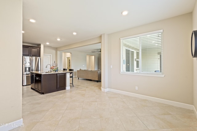 10460 Mott Ct, Reno, NV 89521 - kitchen with stainless steel fridge with ice dispenser, open floor plan, dark brown cabinetry, a center island with sink, and light tile patterned floors