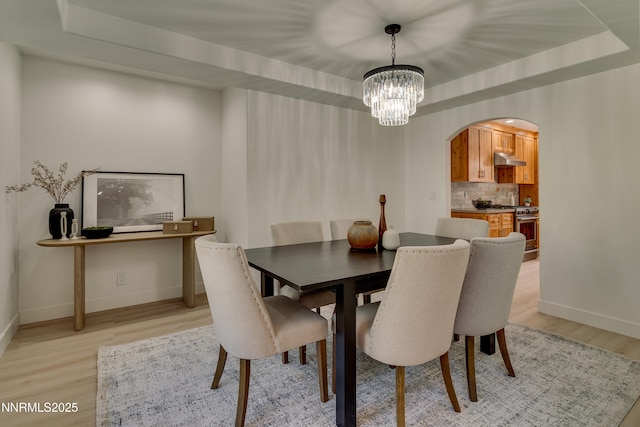 471 Kent Way, Zephyr Cove, NV 89448 - dining room featuring arched walkways, light wood-type flooring, a chandelier, baseboards, and a tray ceiling