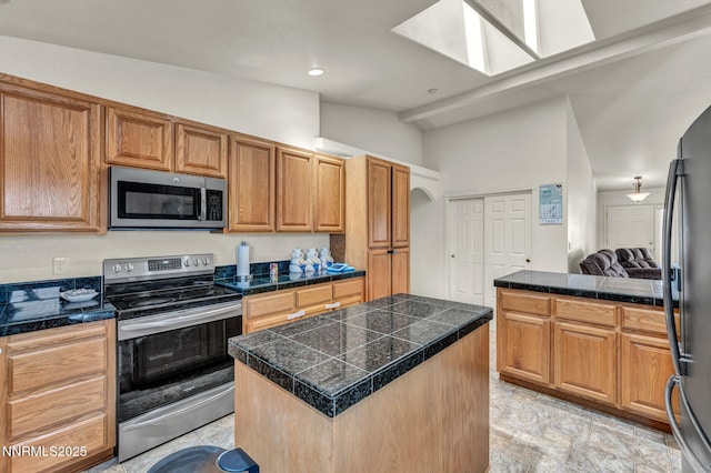 753 Divot Dr, Fernley, NV 89408 - kitchen featuring stainless steel appliances, tile counters, a center island, a skylight, and vaulted ceiling