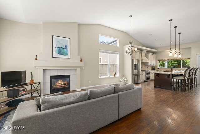 9783 Northrup Dr, Reno, NV 89521 - living room with dark wood-style floors, a tile fireplace, lofted ceiling, and a chandelier