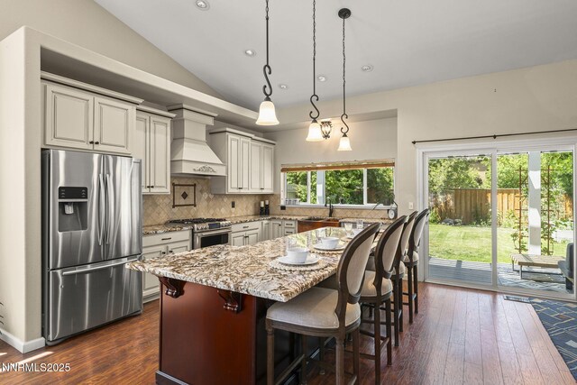 9783 Northrup Dr, Reno, NV 89521 - kitchen featuring stainless steel appliances, premium range hood, dark wood-style flooring, decorative backsplash, and lofted ceiling