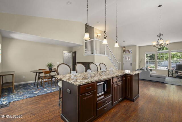 9783 Northrup Dr, Reno, NV 89521 - kitchen with stainless steel microwave, dark wood-style flooring, a breakfast bar area, a chandelier, and lofted ceiling
