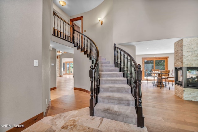 4215 Wild Eagle Ter, Reno, NV 89511 - staircase featuring hardwood / wood-style flooring, a towering ceiling, and a multi sided fireplace