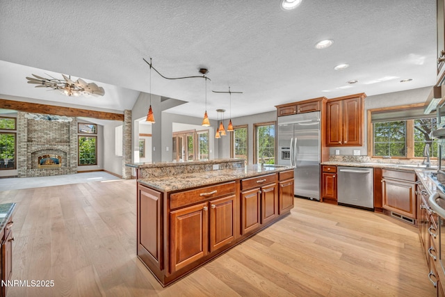 4215 Wild Eagle Ter, Reno, NV 89511 - kitchen featuring stainless steel appliances, light wood-type flooring, a textured ceiling, light stone countertops, and open floor plan
