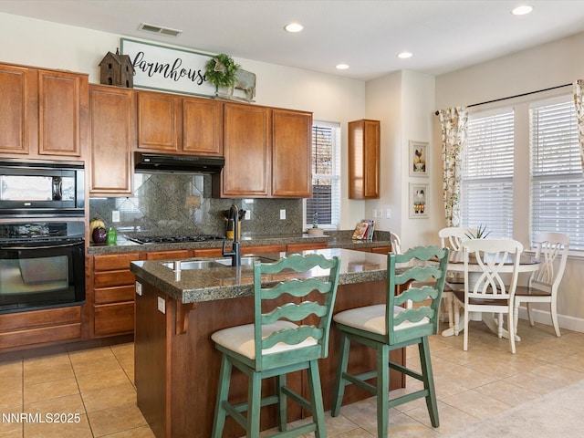 7693 Stone Bluff Way, Reno, NV 89523 - kitchen featuring black appliances, a center island with sink, backsplash, brown cabinetry, and recessed lighting