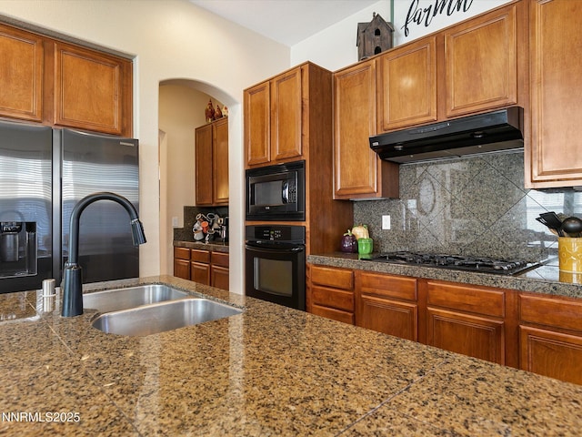 7693 Stone Bluff Way, Reno, NV 89523 - kitchen featuring under cabinet range hood, black appliances, a sink, arched walkways, and decorative backsplash
