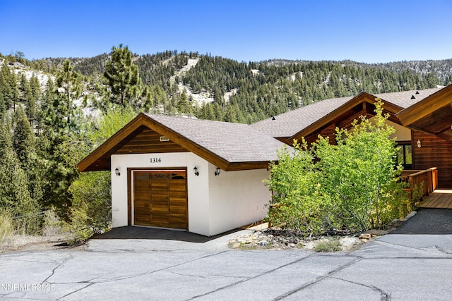 1314 Saint Gallen Ct, Incline Village, NV 89451 - view of front of home featuring stucco siding, a wooded view, roof with shingles, a garage, and a mountain view