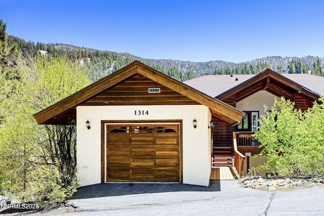 1314 Saint Gallen Ct, Incline Village, NV 89451 - view of front of home with stucco siding, an attached garage, asphalt driveway, and a forest view