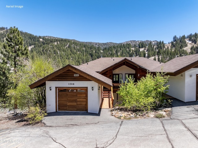 1314 Saint Gallen Ct, Incline Village, NV 89451 - view of front of property with a garage, a mountain view, stucco siding, and a wooded view