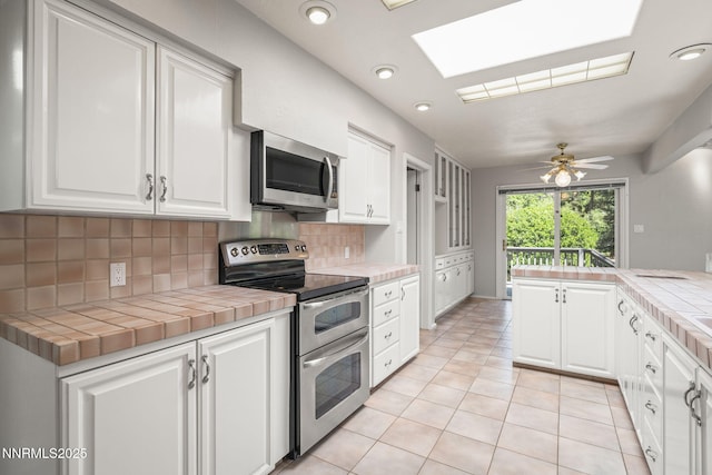 1405 Dartmouth Dr, Reno, NV 89509 - kitchen featuring stainless steel appliances, tile countertops, a skylight, tasteful backsplash, and recessed lighting