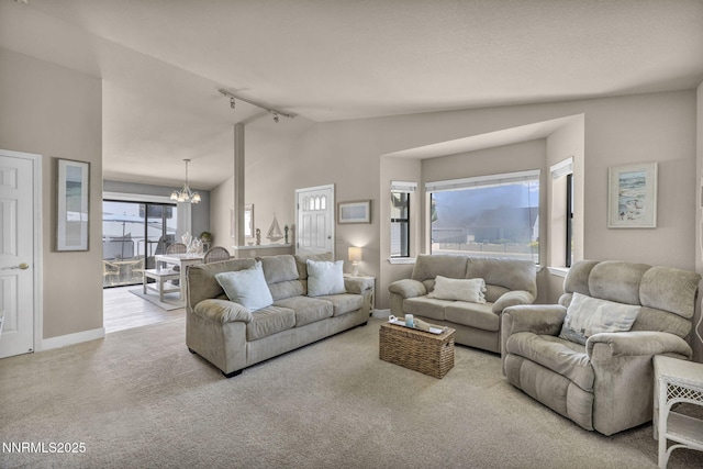 1416 Sally Ln, Gardnerville, NV 89460 - carpeted living area with rail lighting, lofted ceiling, a chandelier, and baseboards