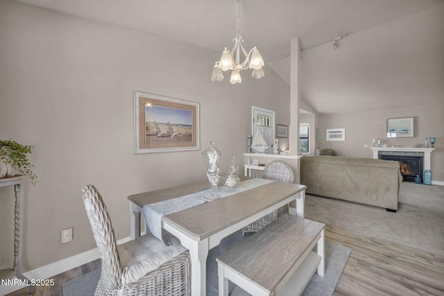 1416 Sally Ln, Gardnerville, NV 89460 - dining room featuring a chandelier, lofted ceiling, baseboards, wood finished floors, and a glass covered fireplace