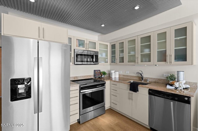 255 N Sierra St Unit 1410, Reno, NV 89501 - kitchen featuring stainless steel appliances, a sink, recessed lighting, light wood finished floors, and glass insert cabinets