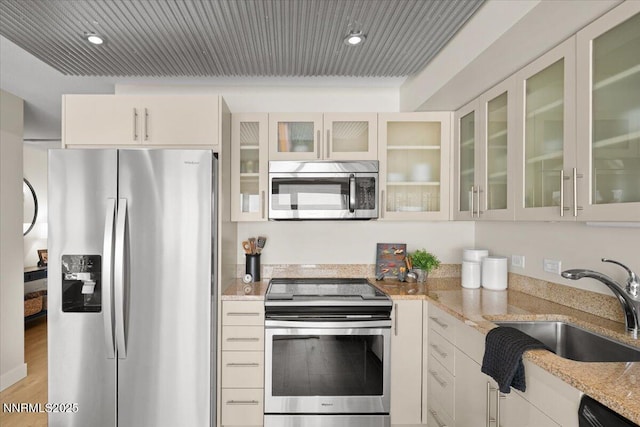 255 N Sierra St Unit 1410, Reno, NV 89501 - kitchen featuring appliances with stainless steel finishes, a sink, light stone counters, glass insert cabinets, and white cabinetry